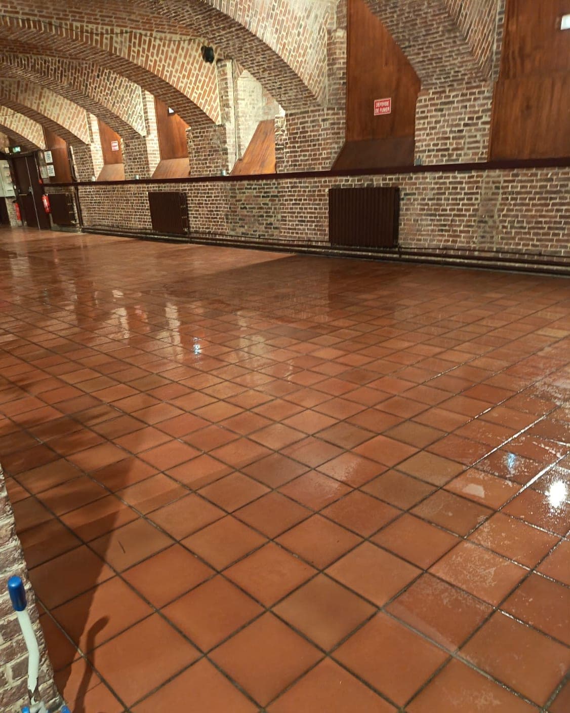 Salle voûtée en briques rouges au sol de terre cuite fraîchement lavé et brillant