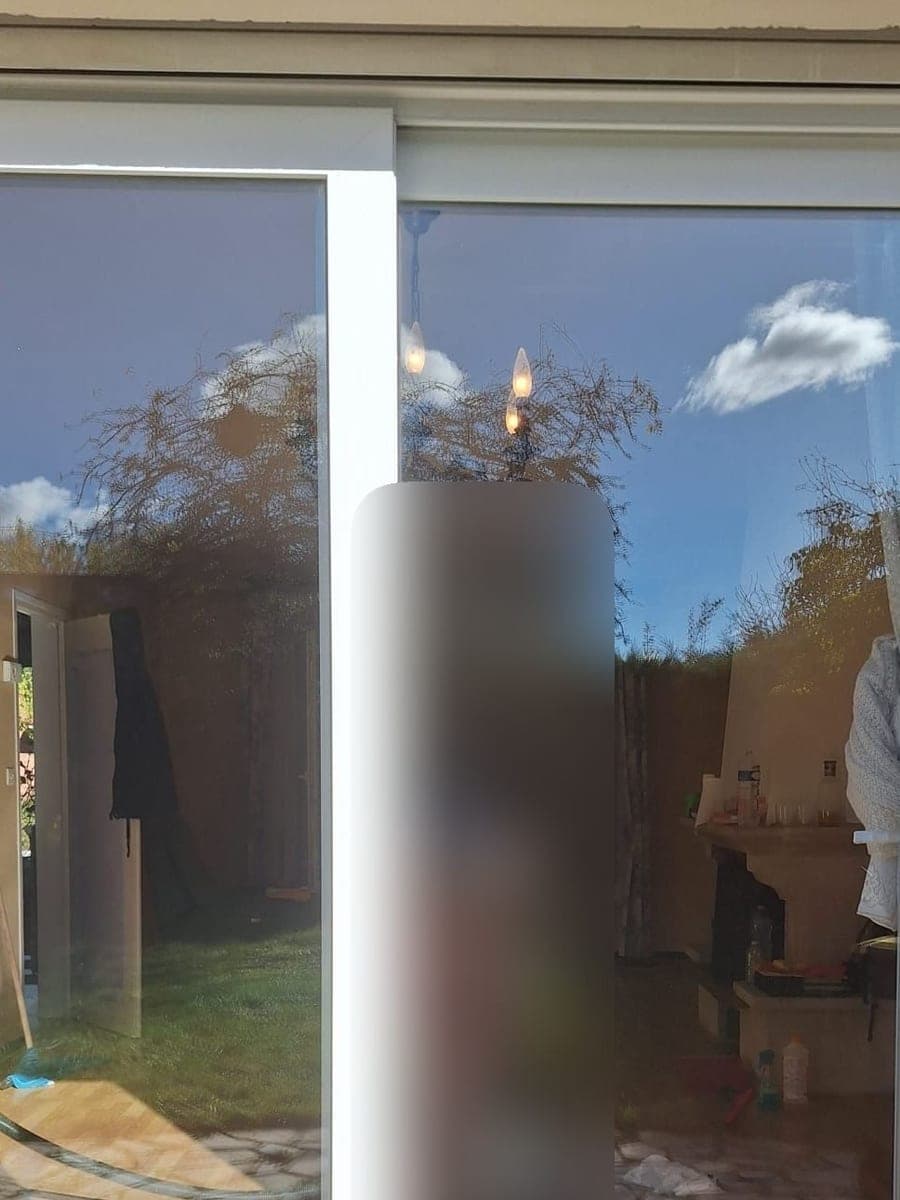 La même baie vitrée coulissante, verre net où se reflètent le ciel et le jardin