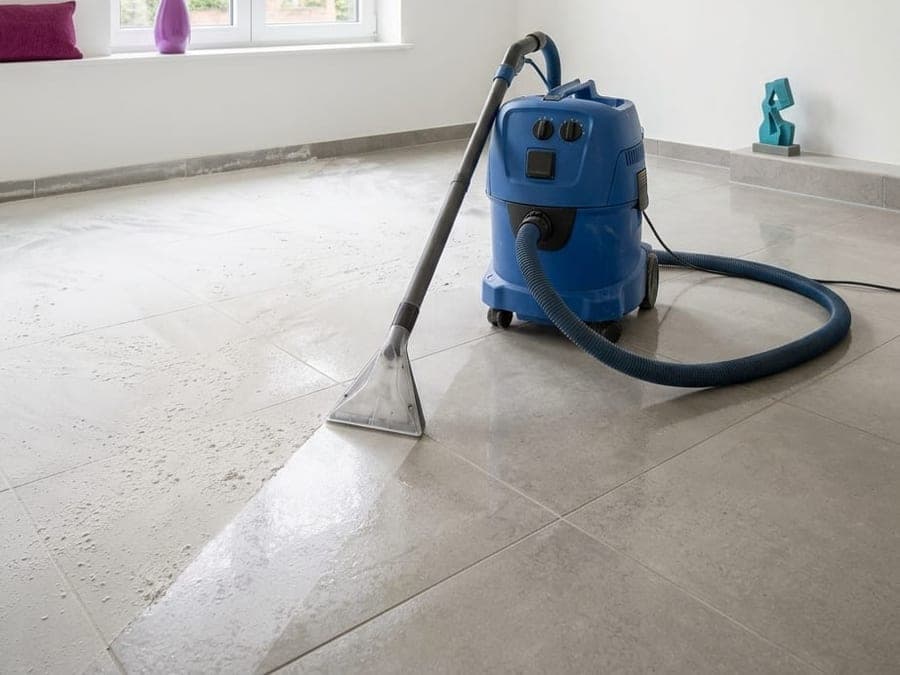 Aspirateur de chantier sur le sol à moitié dépoussiéré d'une pièce rénovée