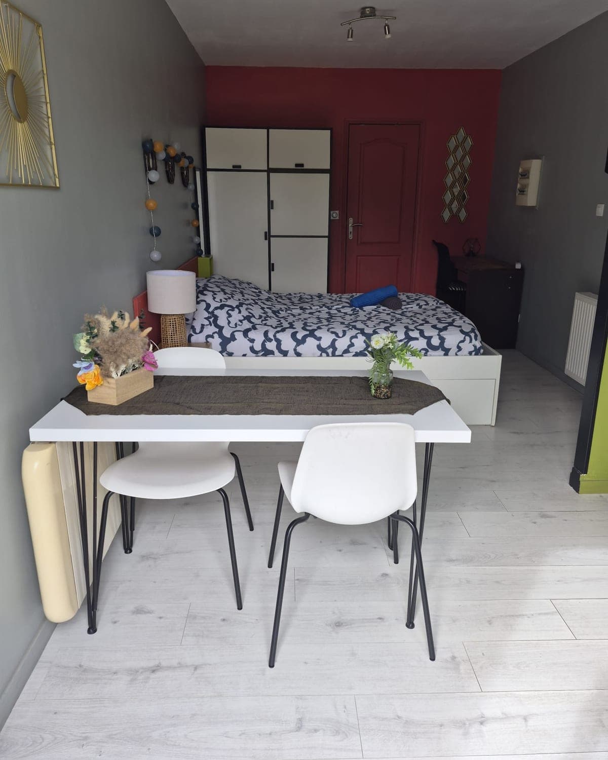 Studio prêt à accueillir : lit double à housse bleu nuit, serviettes roulées, table et chaises blanches