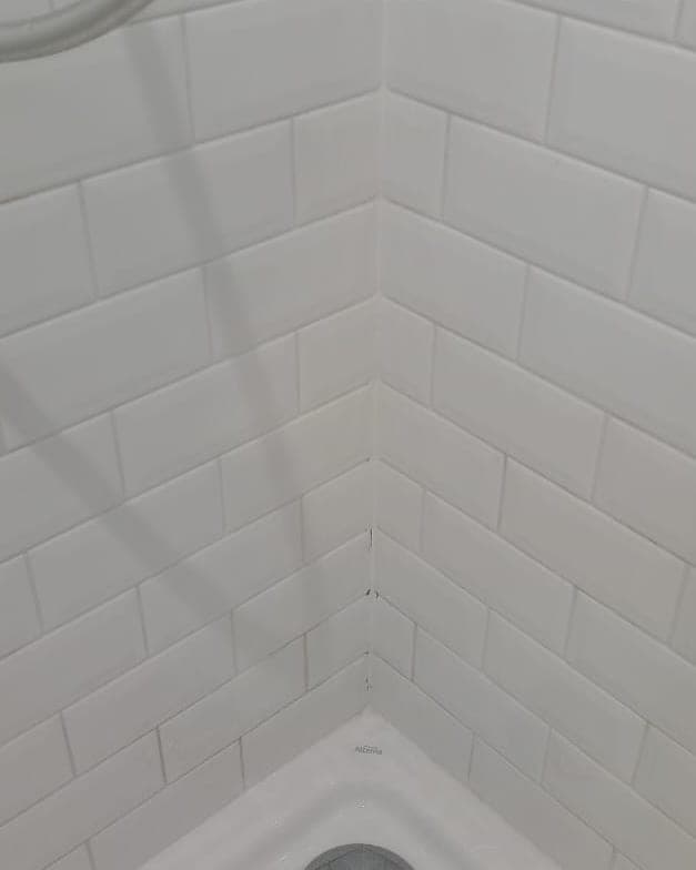 Angle de douche en faïence blanche aux joints redevenus blancs, après le grand nettoyage