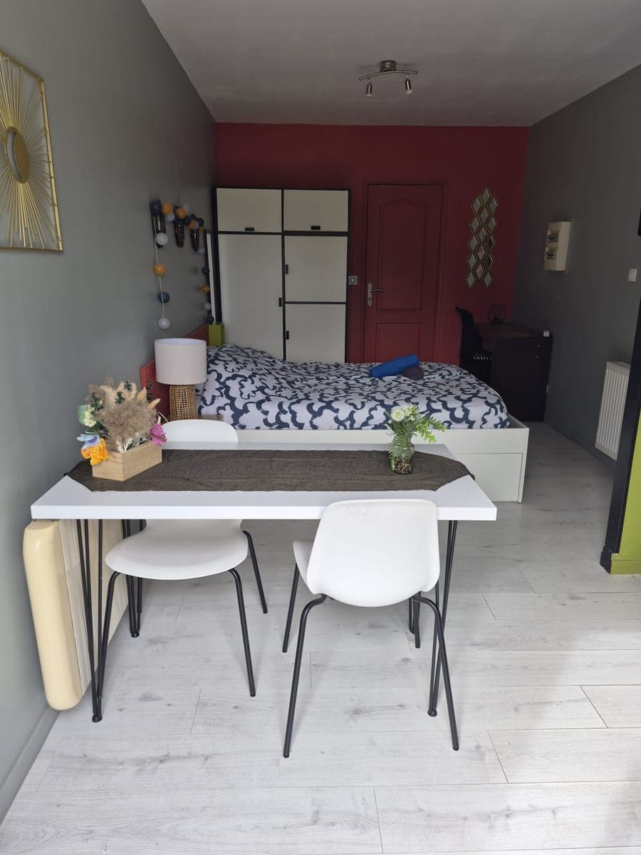 Studio prêt à accueillir : lit double à housse bleu nuit, serviettes roulées, table et chaises blanches